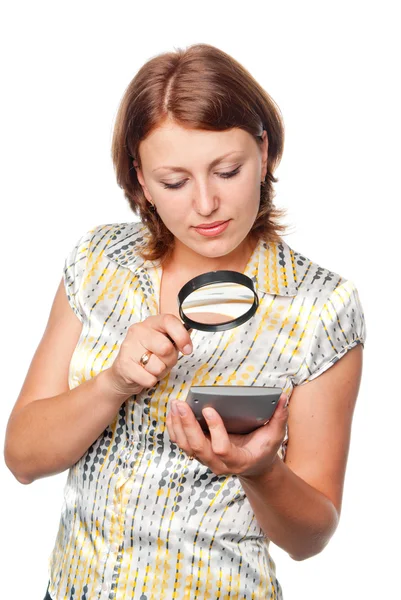Girl looks at the calculator through a magnifier — Stock Photo, Image