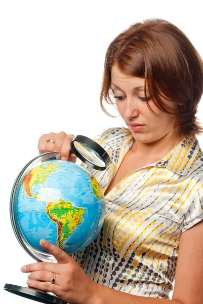 Girl attentively examines the globe through a magnifier Royalty Free Stock Photos