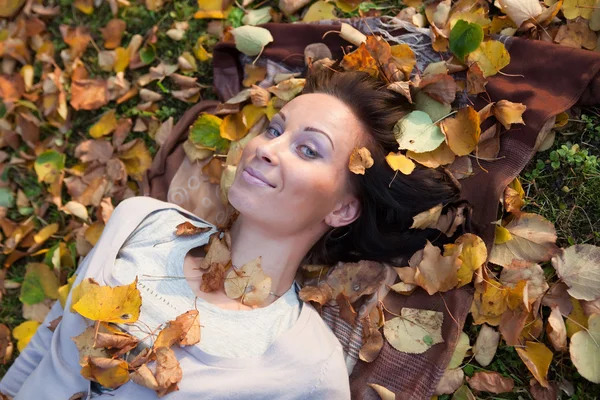 微笑女孩躺在枫叶 免版税图库图片
