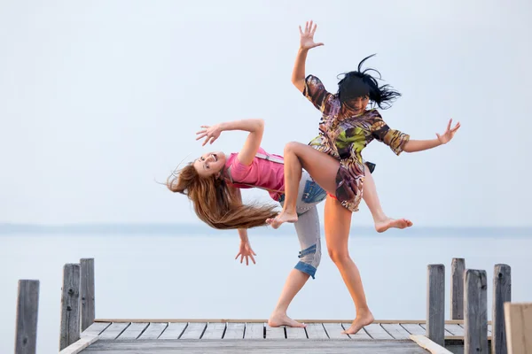 Two girl are dancing on background of water and sky — Stock Photo, Image