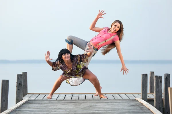 Two girl are dancing on background of water and sky — Stock Photo, Image