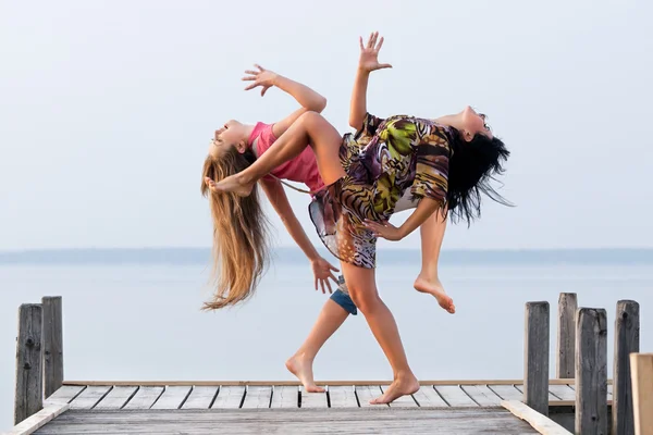 两个女孩在水和天空的背景上跳舞 — 图库照片