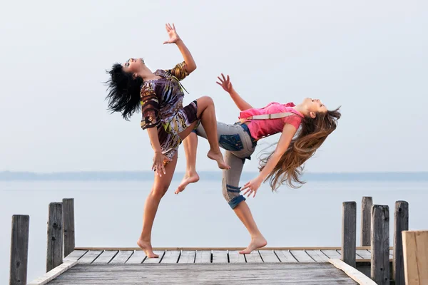 两个女孩在水和天空的背景上跳舞 — 图库照片