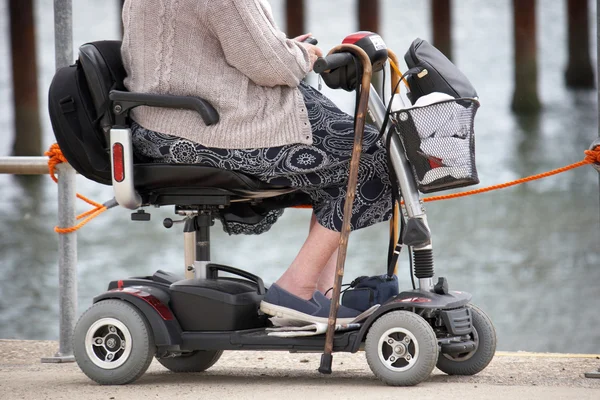 Mujer mayor en la playa en scooter de movilidad Imagen de archivo