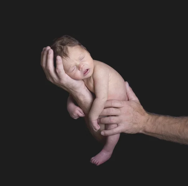 新生儿摇篮里父亲的手与武器 — 图库照片