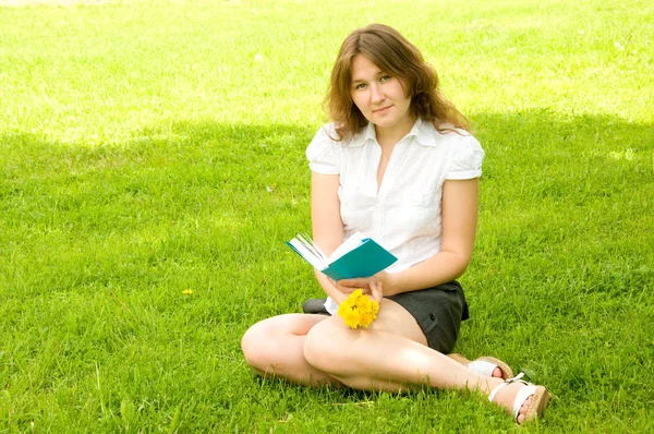 Woman with book on lawn — Stock Photo, Image