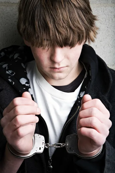 Jugendkriminalität - Kind in Handschellen lizenzfreie Stockbilder