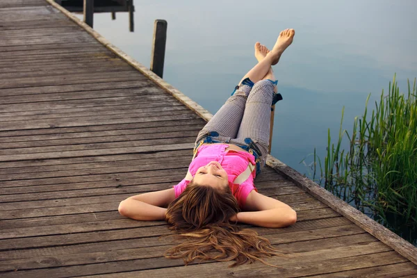 Fiatal nő feküdt a híd a nyári pihenés — Stock Fotó