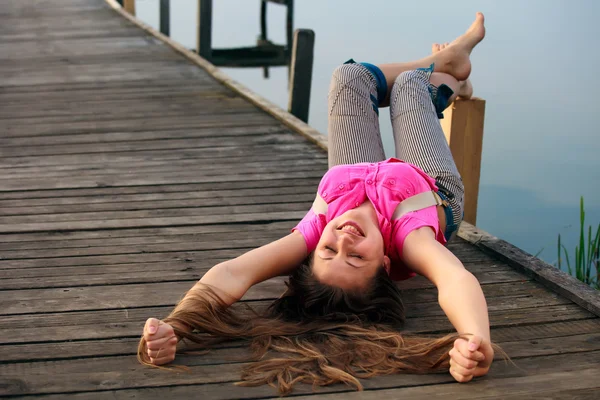 Entspannte junge Frau liegt im Sommer auf der Brücke — Stockfoto