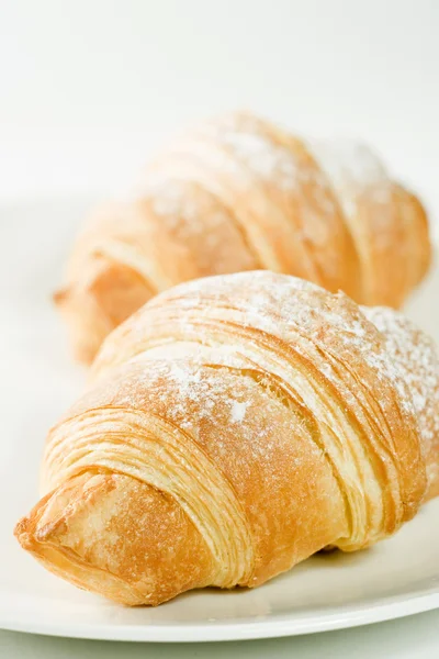 Fresh croissants on white plate with powdered sugar — Stock Photo, Image