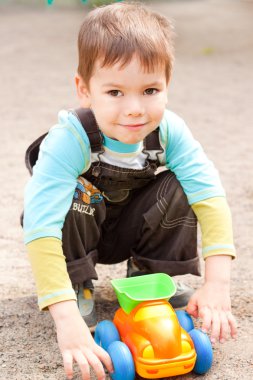 A little boy smiling and playing in the toy car in the children' clipart