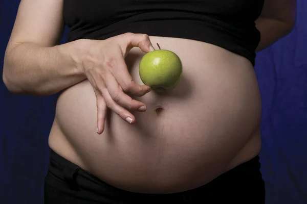 Pregnant belly with apple — Stock Photo, Image