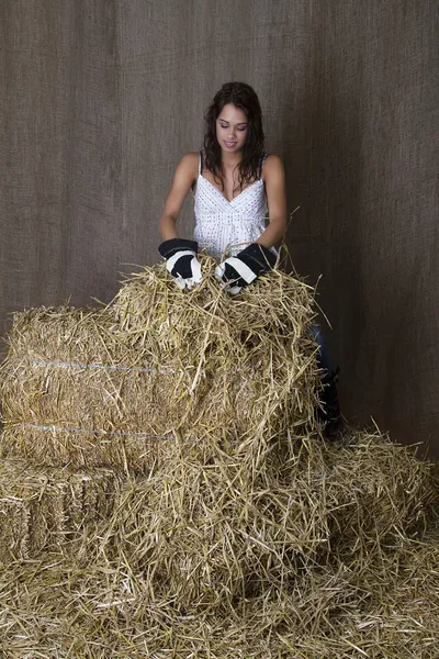深色头发的女人通过捆捆稻草为一根针的搜索 — 图库照片