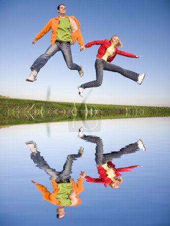 Joyeux couple souriant sautant dans le ciel bleu 