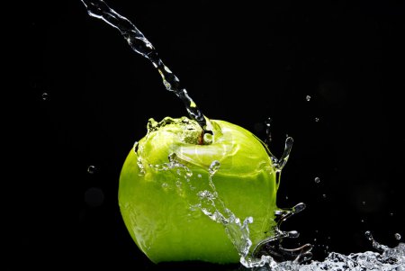 Pomme verte avec éclaboussure d'eau sur fond noir 