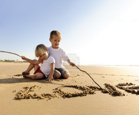 Enfants écrivant dans le sable 