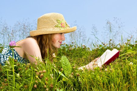 Jeune fille lecture livre dans prairie 