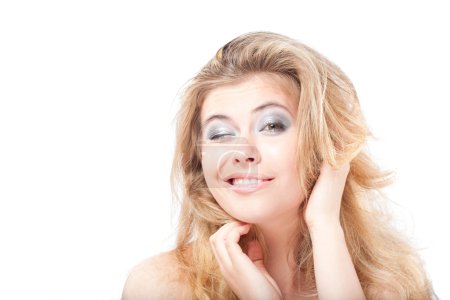 Winking femme blonde souriante tenant les cheveux avec les mains 